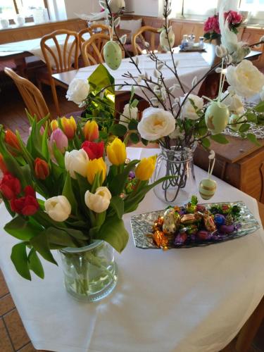 a white table with a vase of flowers on it at Pension Breidbach in Ensch