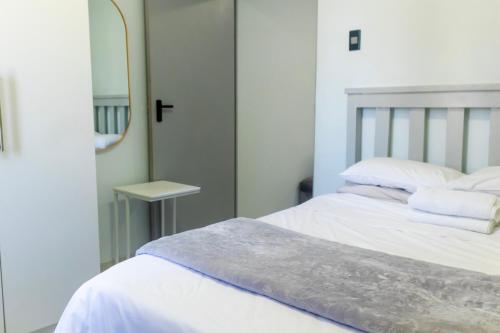 Un dormitorio con una cama blanca y un espejo. en Grace Villas 7, en East London