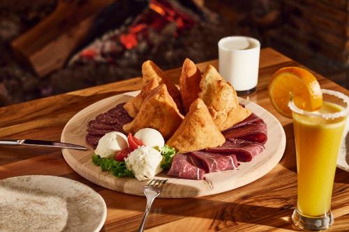 a plate of food with meat and eggs and a drink at Hotel Han Bjelašnica in Bjelašnica
