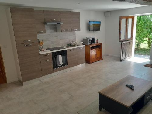 une grande cuisine avec des placards en bois et une table dans l'établissement Agréable et jolie maison avec grand jardin, à Pellevoisin