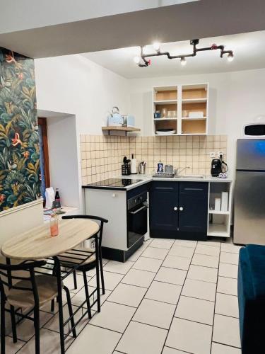 Il comprend une cuisine équipée d'une table, d'un réfrigérateur, d'une table et de chaises. dans l'établissement Duplex charmant au coeur de Levroux, à Levroux