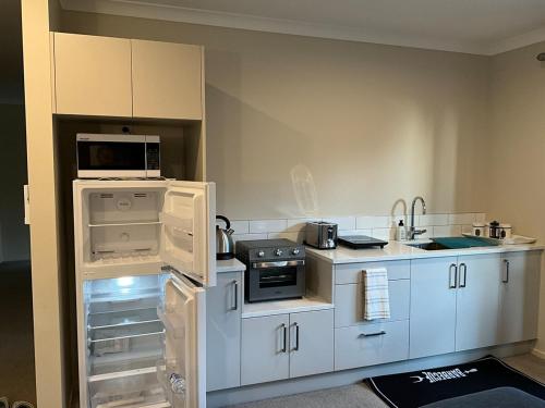 a small kitchen with white cabinets and appliances at New two Bedroom house attached to main house in Pukekohe East
