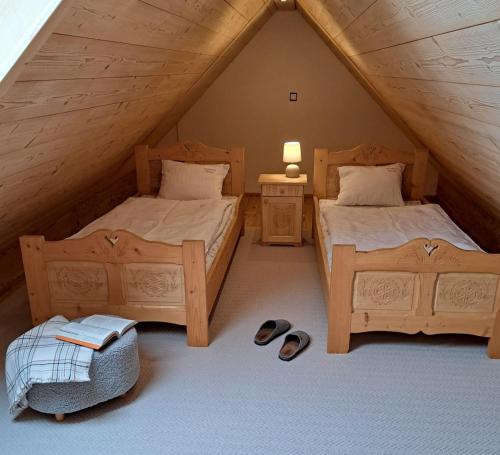 a attic bedroom with two beds and a night stand at Apartamenty Ancymon in Węgierska Górka