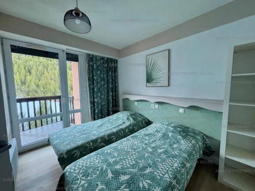 une chambre avec deux lits et une grande fenêtre dans l'établissement Appartement F2/cabine pieds des pistes avec balcon, parking privé et accès internet - Les Angles - FR-1-295-197, aux Angles