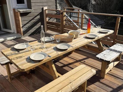 - une table de pique-nique en bois avec des assiettes et des verres sur une terrasse dans l'établissement Chalet alpin spacieux avec parking, proche télécabine - FR-1-812-97, à Cauterets