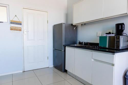 una cucina con mobili bianchi e un frigorifero di CZ Kubs 43 a East London