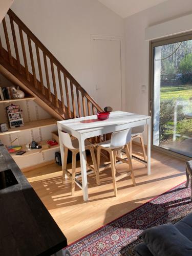 une table et des chaises blanches dans une pièce avec un escalier dans l'établissement Entre Bordeaux et l'océan, à Salles
