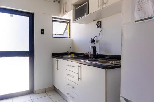 Una cocina con gabinetes blancos y una encimera negra. en Grace Villas 28, en East London