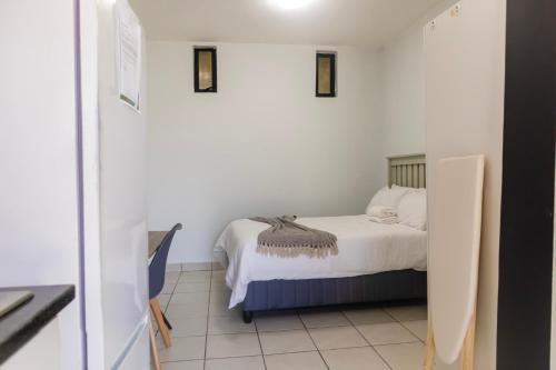 a small bedroom with a bed with white sheets at Grace Villas 28 in East London