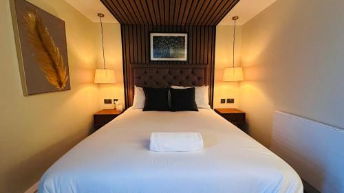 a bedroom with a large white bed with two lamps at The Suffolk Hotel in Haverhill