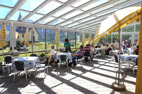 a group of people sitting at tables in a greenhouse at Piccolo Hotel Gurschler in Maso Corto