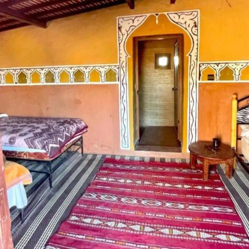 a bedroom with a bed and a table and a rug at Mhamid camp happy night in Mhamid