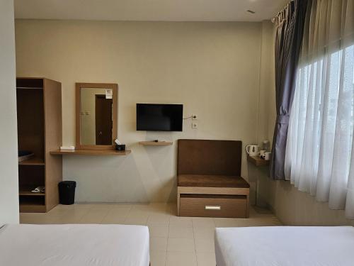 a hotel room with two beds and a television at Amerta Giri Hotel Dieng Wonosobo in Kejajar