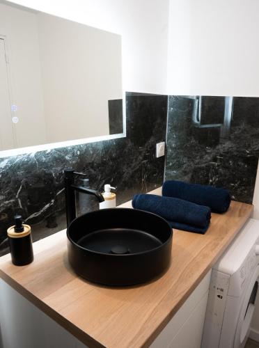 La salle de bains est pourvue d'un lavabo noir. dans l'établissement L' escale SAINT ANNE, à Reims