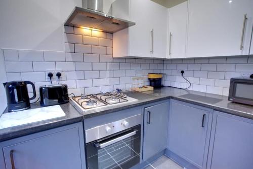a kitchen with white cabinets and a stove top oven at Sleeps 18 Lovely Mcr Home by City SuperHost in Manchester