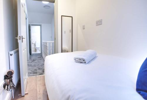 a white bedroom with a bed and a mirror at Sleeps 18 Lovely Mcr Home by City SuperHost in Manchester