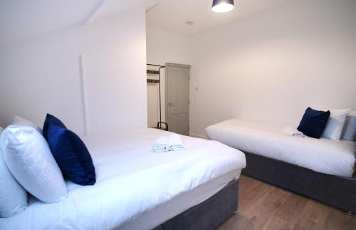 two beds with blue pillows in a room at Sleeps 18 Lovely Mcr Home by City SuperHost in Manchester