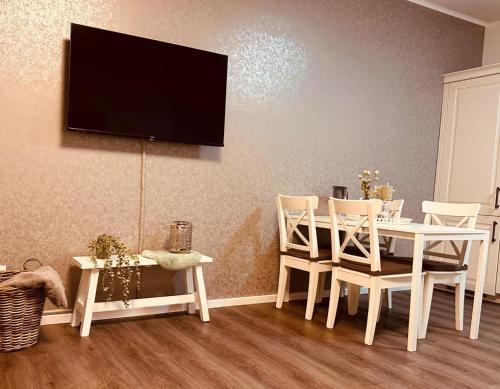 a dining room with a white table and chairs and a tv at Fewo-Romuli in Eggesin