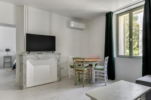 a living room with a television and a table with chairs at Le Bambou Wifi Proche des pontons et du Doul in Peyriac-de-Mer