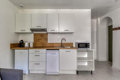 a kitchen with white cabinets and a sink at Le Bambou Wifi Proche des pontons et du Doul in Peyriac-de-Mer