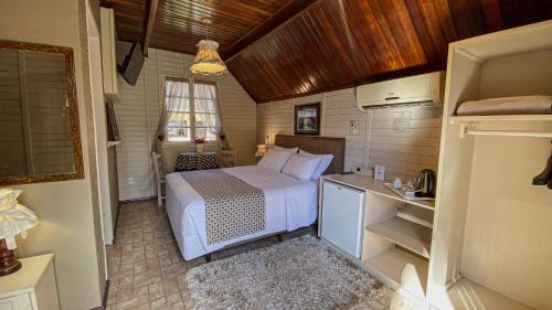 a small bedroom with a bed and a desk at Pousada Caliandra Da Serra in Canela