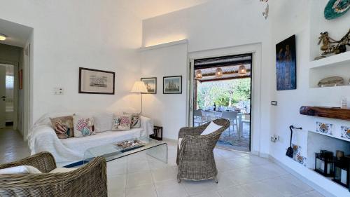 a living room with a white couch and chairs at Villa la Bonaccia in La Maddalena