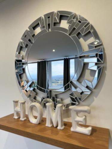 a large circular mirror on a shelf with a table at Two Bedroom Flat by Brookland Stays Serviced Accommodation Short Lets Leeds with Free WiFi in Yeadon