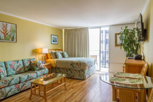 a hotel room with a bed and a couch at Tropical Studios at Marine Surf Waikiki - FREE PARKING - BEST LOCATION - FULL KITCHEN - SWIMMING POOL in Honolulu