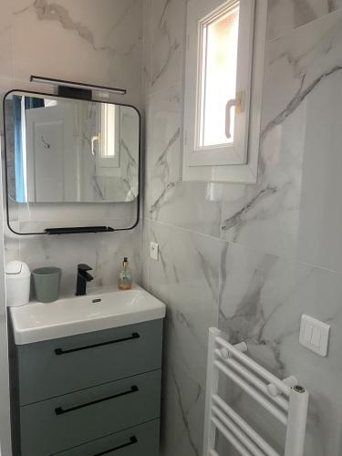 une salle de bain blanche avec un lavabo et un miroir dans l'établissement VILLA climatisée calme avec bassin privé et grande piscine partagée à ST AYGULF FREJUS, à Fréjus