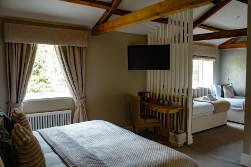 a bedroom with a bed and a tv on the wall at Manor House Hotel in Bishop Auckland