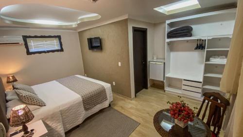 a bedroom with a bed and a table and a room with a kitchen at Pousada Caliandra Da Serra in Canela