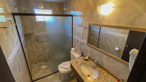 a bathroom with a shower and a sink and a toilet at Pousada Caliandra Da Serra in Canela