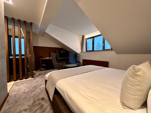 a bedroom with a large white bed and windows at Hôtel Restaurant & Spa Les Planets in Les Rasses