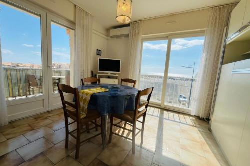 une salle à manger avec une table, des chaises et des fenêtres dans l'établissement Appartement les pieds dans l'eau Terrasse Mer, à Fleury