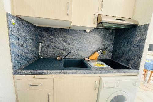 Il comprend une cuisine équipée d'un évier et d'une cuisinière. dans l'établissement Appartement les pieds dans l'eau Terrasse Mer, à Fleury