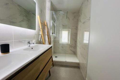 une salle de bain blanche avec un lavabo et une douche dans l'établissement L'Horreum Appartement proche des Halles Wifi, à Narbonne