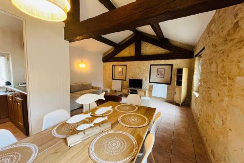 une salle à manger avec une table en bois et des chaises blanches dans l'établissement L'Horreum Appartement proche des Halles Wifi, à Narbonne