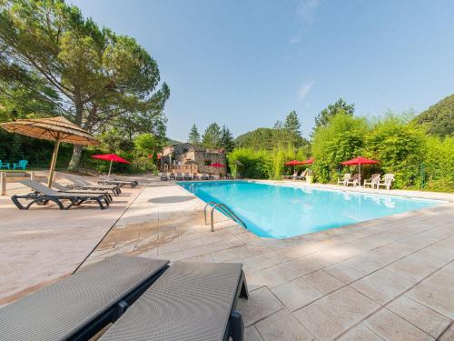- une piscine avec des bancs et des parasols dans un complexe dans l'établissement Domaine Résidentiel de Plein Air Mas de Champel, aux Ollières-sur-Eyrieux