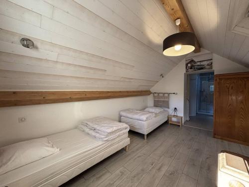two beds in a room with wooden walls at Maison confortable à Villard-de-Lans - 8 couchages, WiFi, parking gratuit, proche des pistes et du centre. - FR-1-548-5 in Villard-de-Lans