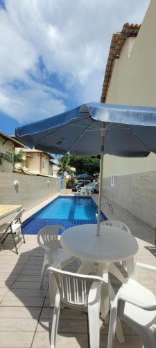 un tavolo e sedie con ombrellone accanto a una piscina di Loft casa 203 COND BRISAS DO FAROL n 07 a Salvador