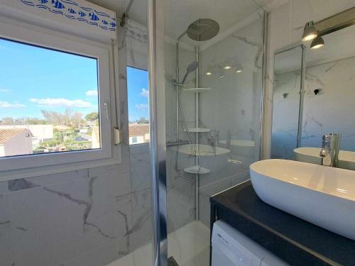 une salle de bain avec un lavabo et une douche en verre dans l'établissement Appartement 2 pièces mezzanine climatisé avec piscine et parking privé à Marseillan - FR-1-326-789, à Marseillan