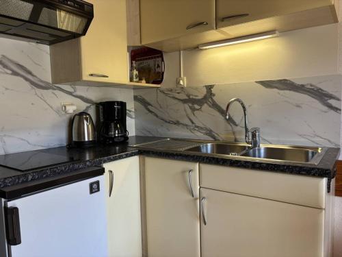 une cuisine avec des armoires blanches et un évier dans l'établissement Studio mezzanine avec balcon et parking privé au cœur de Villard-de-Lans - FR-1-548-28, à Villard-de-Lans