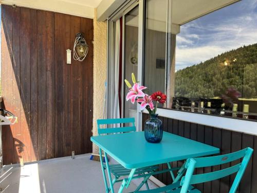 une table bleue et des chaises sur une terrasse couverte avec un vase de fleurs dans l'établissement Studio confortable, idéal pour 4, avec balcon, proche pistes et centre bourg ! - FR-1-548-35, à Villard-de-Lans