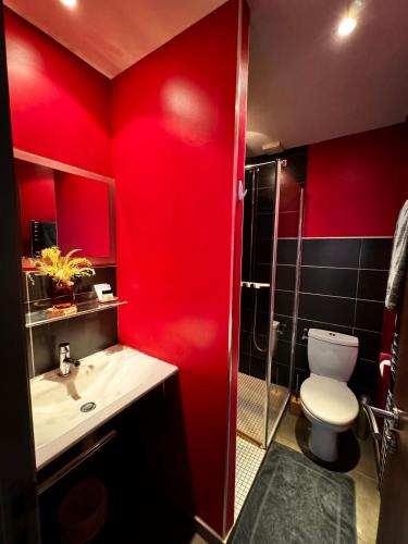 La salle de bains rouge est pourvue de toilettes et d'un lavabo. dans l'établissement Hotel le 116, à Gravelines