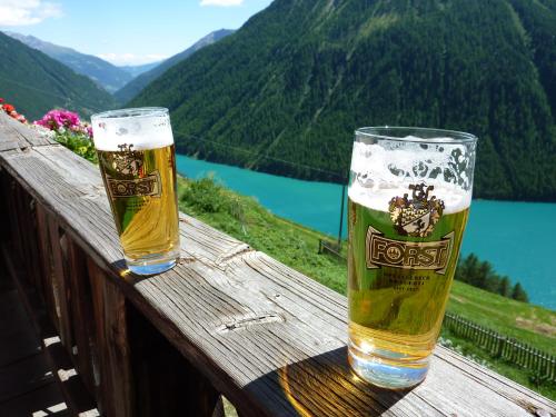 two glasses of beer sitting on a wooden rail at Piccolo Hotel Gurschler in Maso Corto