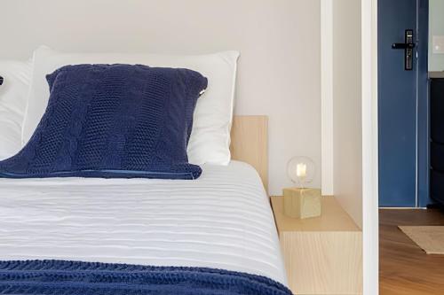 a bed with blue and white sheets and a blue pillow at Nik Perdizes in Sao Paulo