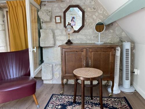 Cette chambre comprend une chaise, une table et un miroir. dans l'établissement Le Refuge des Châteaux, à Chinon