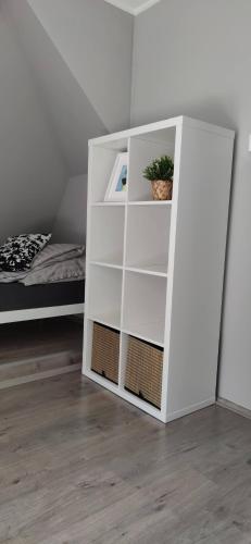 a white book shelf in a room with a bed at Bathy Ház in Tiszakécske