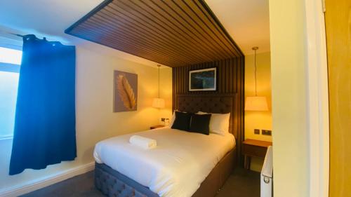 a bedroom with a large bed with a blue curtain at The Suffolk Hotel in Haverhill