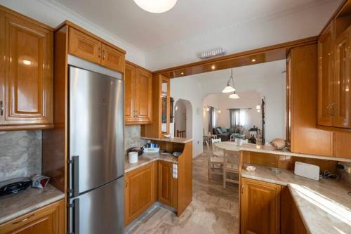 a kitchen with wooden cabinets and a stainless steel refrigerator at Black Coast Santorini in Perivolos